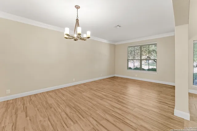 a view of empty room with wooden floor ceiling fan and window