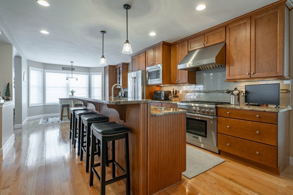 9 Pilgrim Circle Nashua, NH 03063 - Photo 7 of 39 a kitchen with granite countertop wooden floors and wooden cabinets