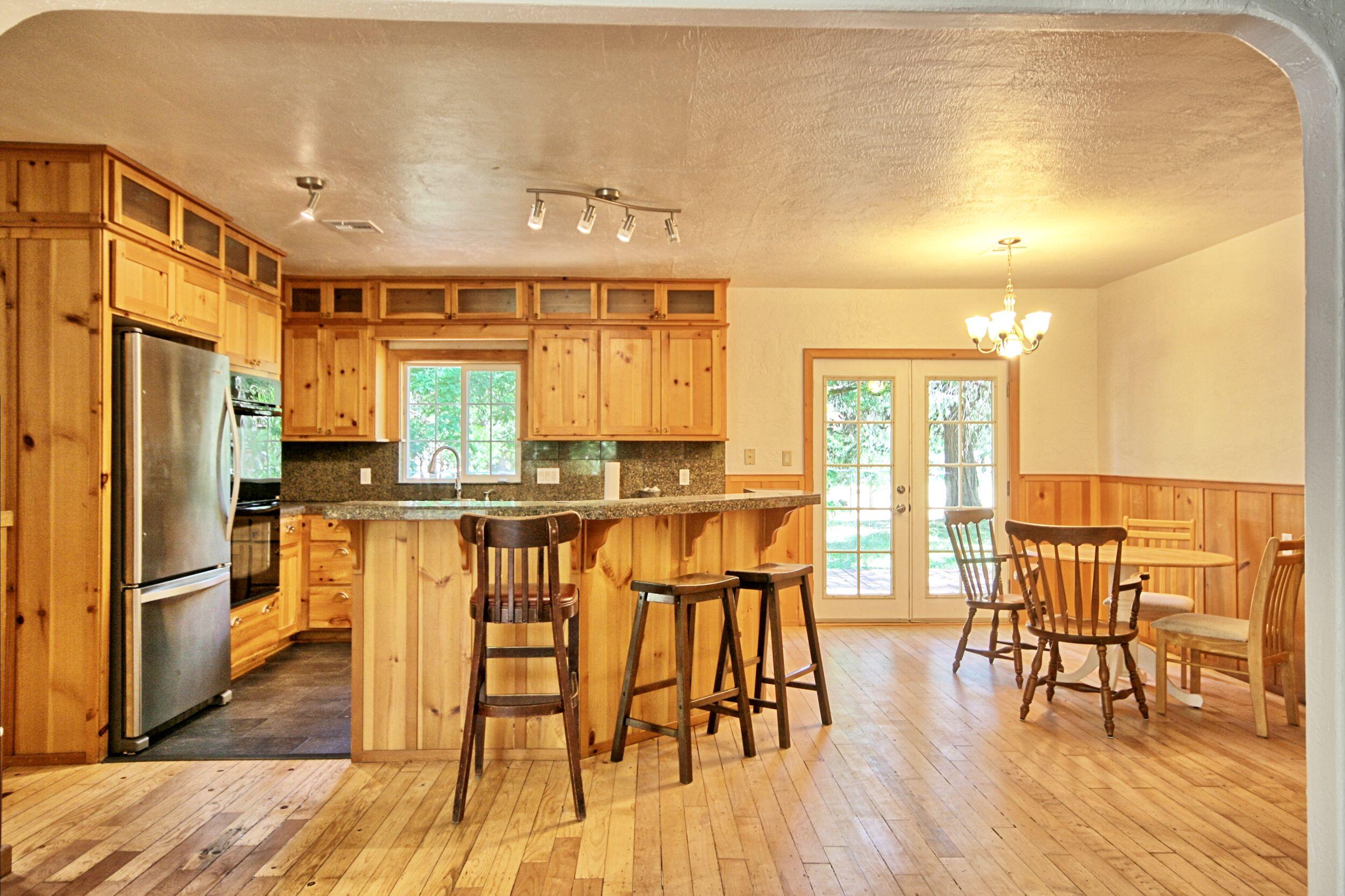 199 Powell Creek Road Williams, OR 97544 - Photo 18 of 57 a kitchen with stainless steel appliances granite countertop a stove a refrigerator a dining table and chairs with wooden floor