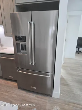 a view of a refrigerator in kitchen and an empty room