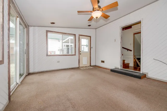 an empty room with windows and ceiling fan