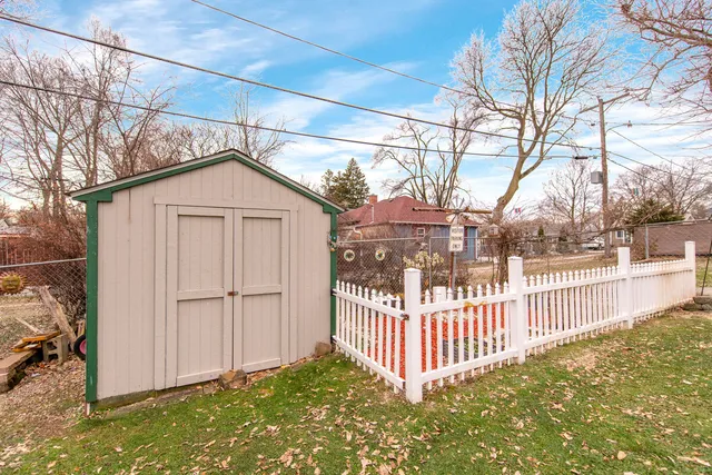 a view of a wooden house with a small yard and wooden fence