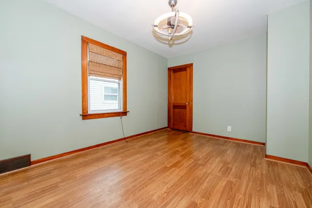 a view of empty room with wooden floor and chandelier