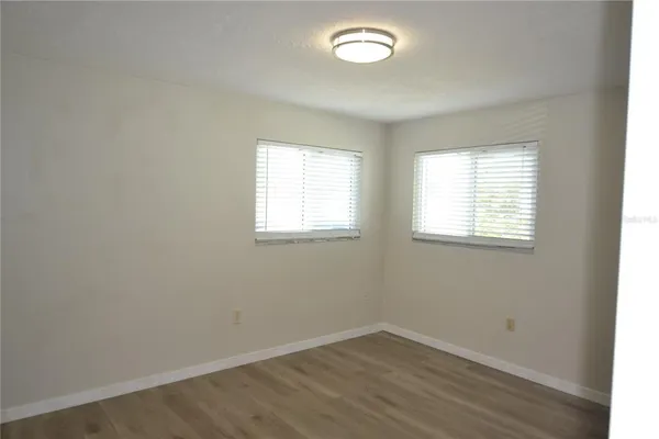 an empty room with wooden floor and window