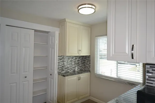 a kitchen with white cabinets and window