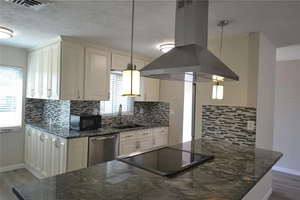 a kitchen with stainless steel appliances kitchen island granite countertop a sink stove and cabinets