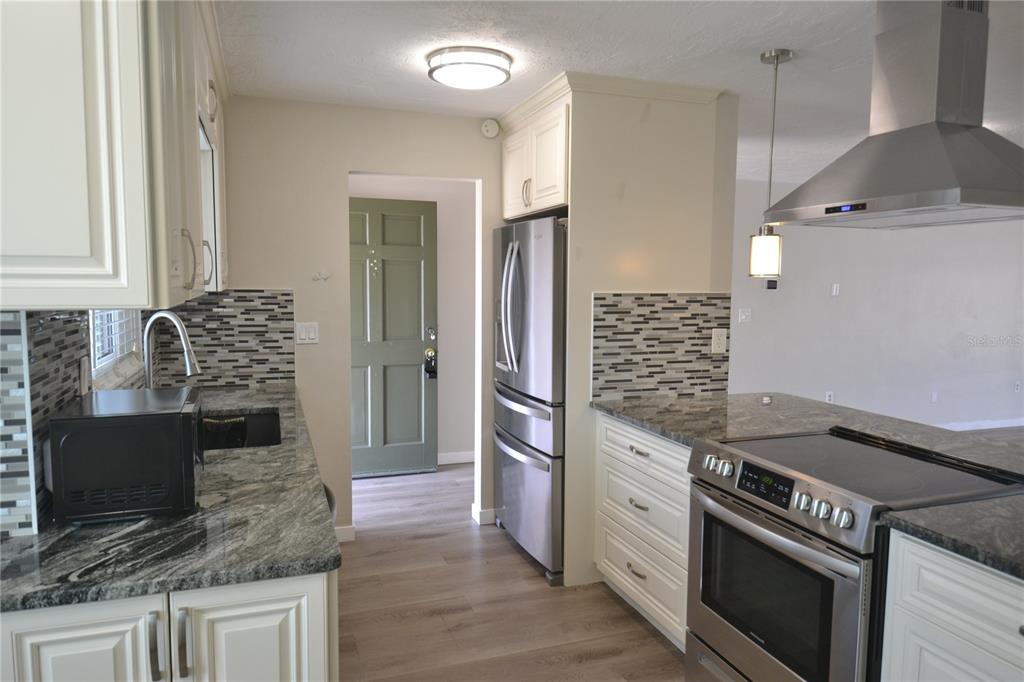 746 Barbara Street Palm Harbor, FL 34684 - Photo 29 of 54 a kitchen with stainless steel appliances granite countertop a stove microwave and refrigerator