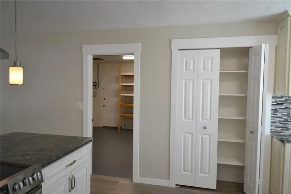 an empty room with wooden floor closet and windows