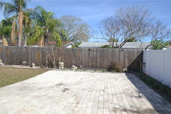 a view of an empty room with kitchen and a window