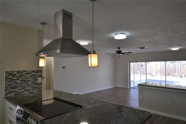a kitchen with kitchen island a counter space a stove and a window