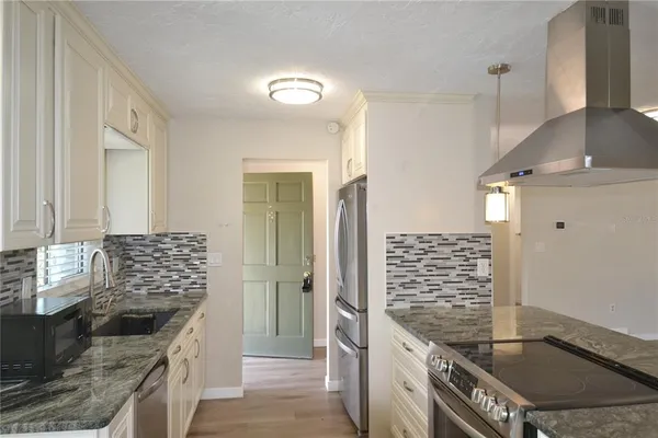 a kitchen with granite countertop a sink stove and refrigerator
