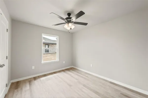 an empty room with windows and fan