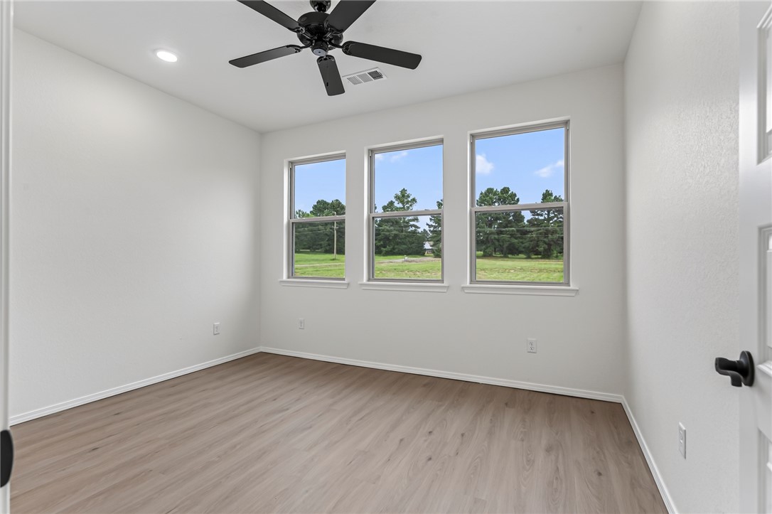 6138 New Hope Road Hackett, AR 72937 - Photo 17 of 56 Wood-finish flooring, three windows with white trim, a recessed ceiling light, and a black ceiling fan