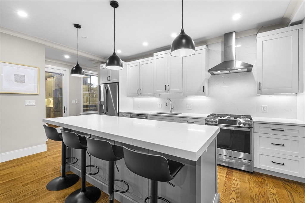 24 Selkirk Road, Unit 244 Boston, MA 02135 - Photo 2 of 31 a kitchen with stainless steel appliances granite countertop a stove a refrigerator a oven a sink with a countertop and chairs
