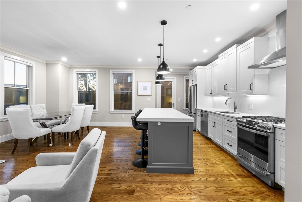 24 Selkirk Road, Unit 244 Boston, MA 02135 - Photo 5 of 31 a large kitchen with stainless steel appliances granite countertop a stove a sink dishwasher a dining table and chairs with wooden floor