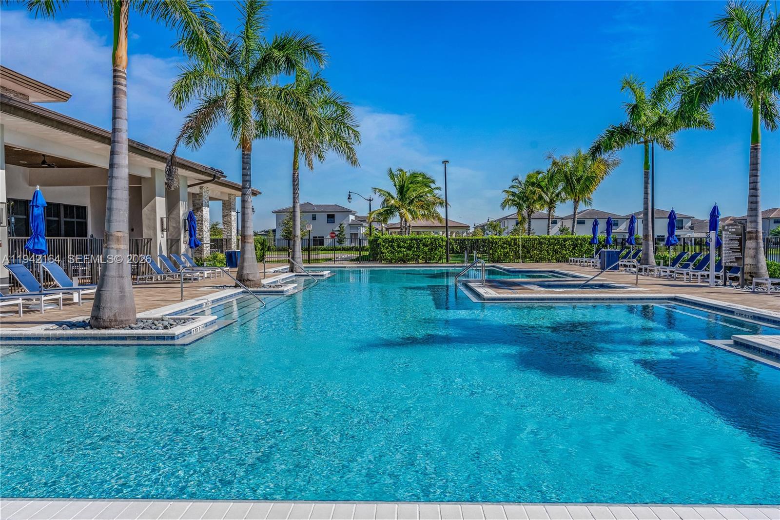 17375 Southwest 41st Street Miramar, FL 33029 - Photo 53 of 53 a view of a swimming pool with a lawn chairs under palm trees