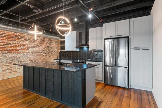a kitchen with granite countertop wooden floors stainless steel appliances a sink and cabinets