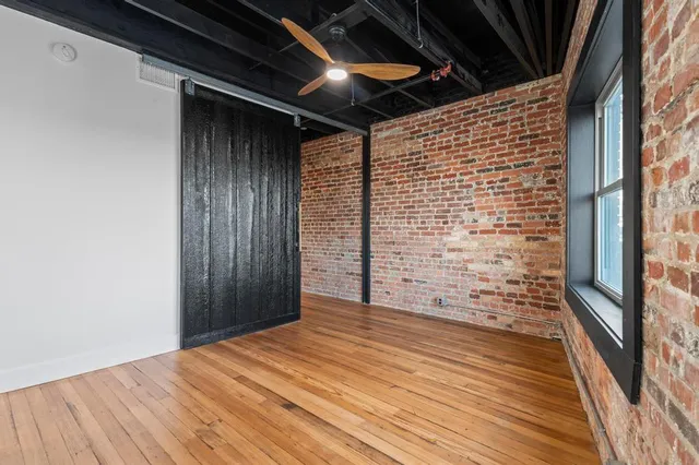 a view of empty room with wooden floor and a window