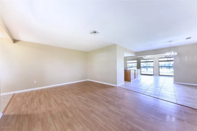 a view of an empty room with window and chandelier fan