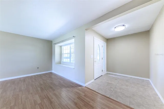 an empty room with wooden floor mirror and window