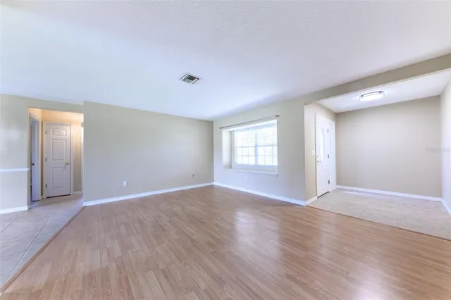a view of an empty room with wooden floor and window