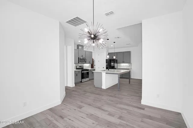 a view of an empty room with wooden floor and window