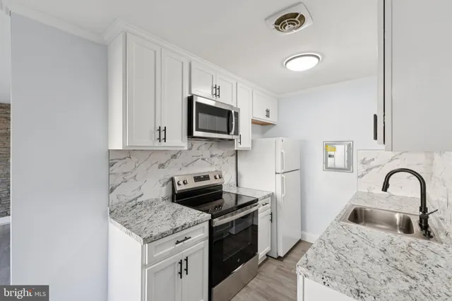 a kitchen with granite countertop a sink and a stove top oven with wooden floor