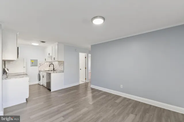 a view of a kitchen with white cabinets and wooden floor