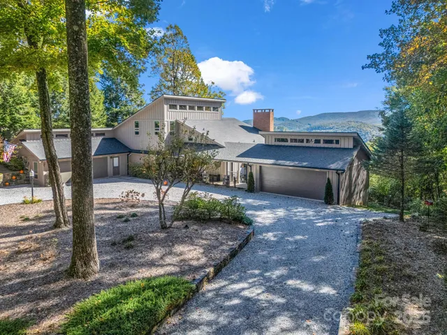a front view of a house with a yard and large tree