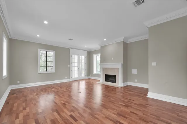 an empty room with wooden floor fireplace and windows