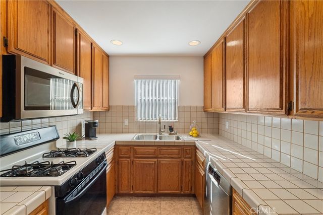 a kitchen with stainless steel appliances a sink a stove cabinets and a window