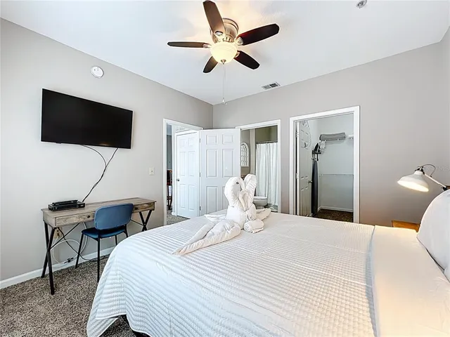 a bedroom with a bed a flat screen tv and a chandelier