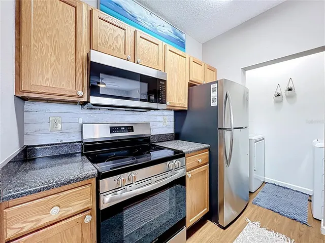 a kitchen with granite countertop a refrigerator stove and microwave