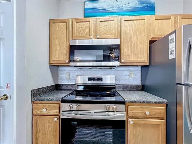 a kitchen with granite countertop wood cabinets stainless steel appliances and a window