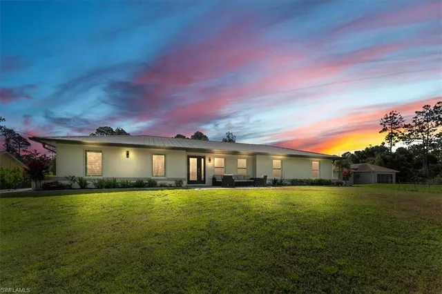 a view of a house with a yard and a large tree