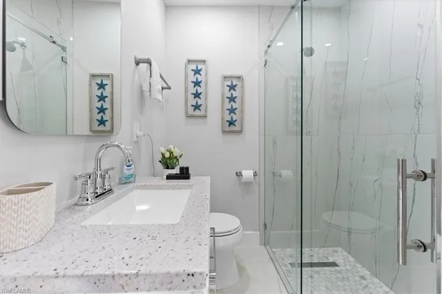a bathroom with a granite countertop sink a toilet and shower