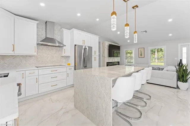 a large kitchen with stainless steel appliances kitchen island granite countertop a refrigerator a stove a oven and white cabinets with wooden floor