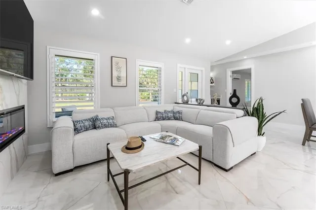 a living room with furniture a flat screen tv and a window