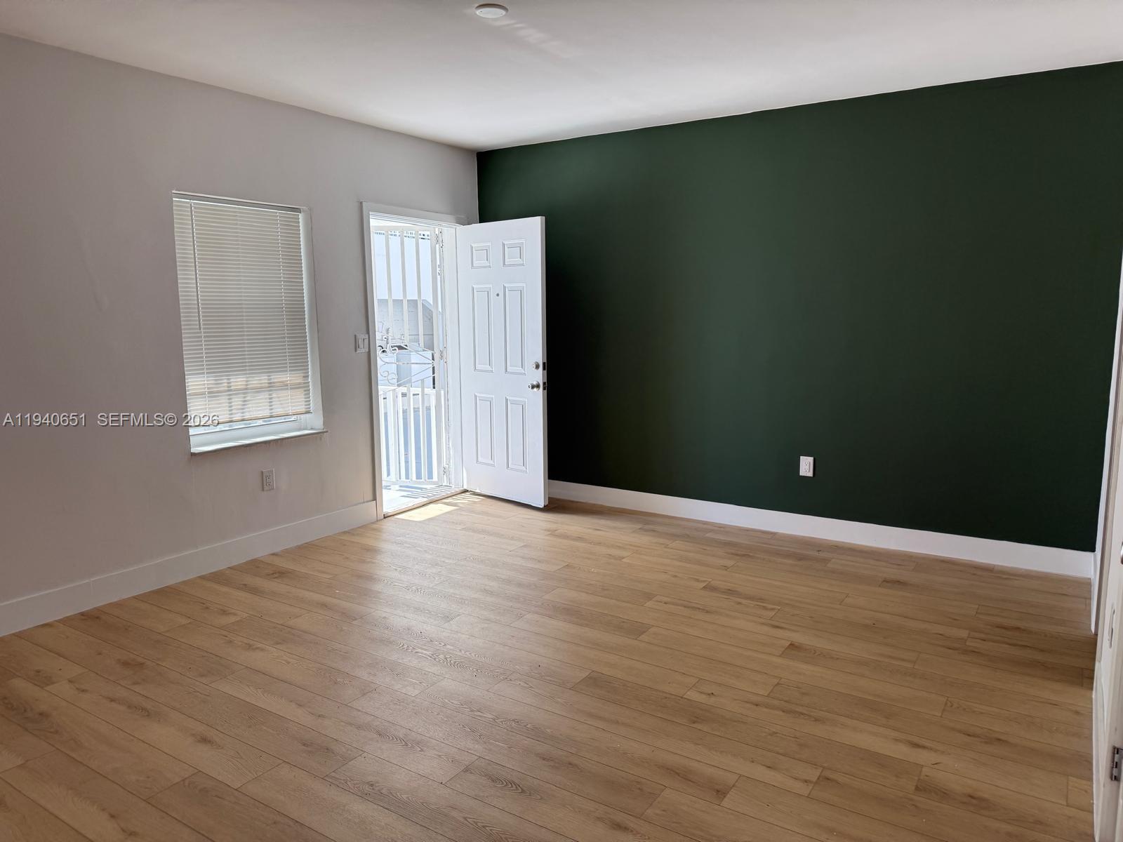 7611 Harding Avenue, Unit 5 Miami Beach, FL 33141 - Photo 5 of 15 an empty room with wooden floor and windows