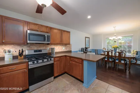 a kitchen with stainless steel appliances granite countertop a stove top oven a sink dishwasher a dining table and chairs with wooden floor