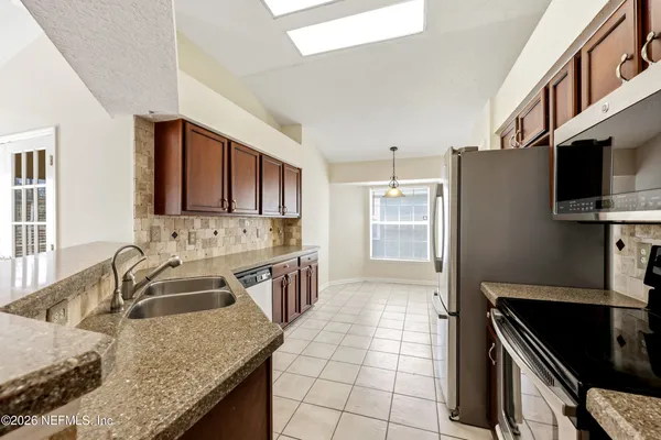 a kitchen with granite countertop a sink stove and refrigerator