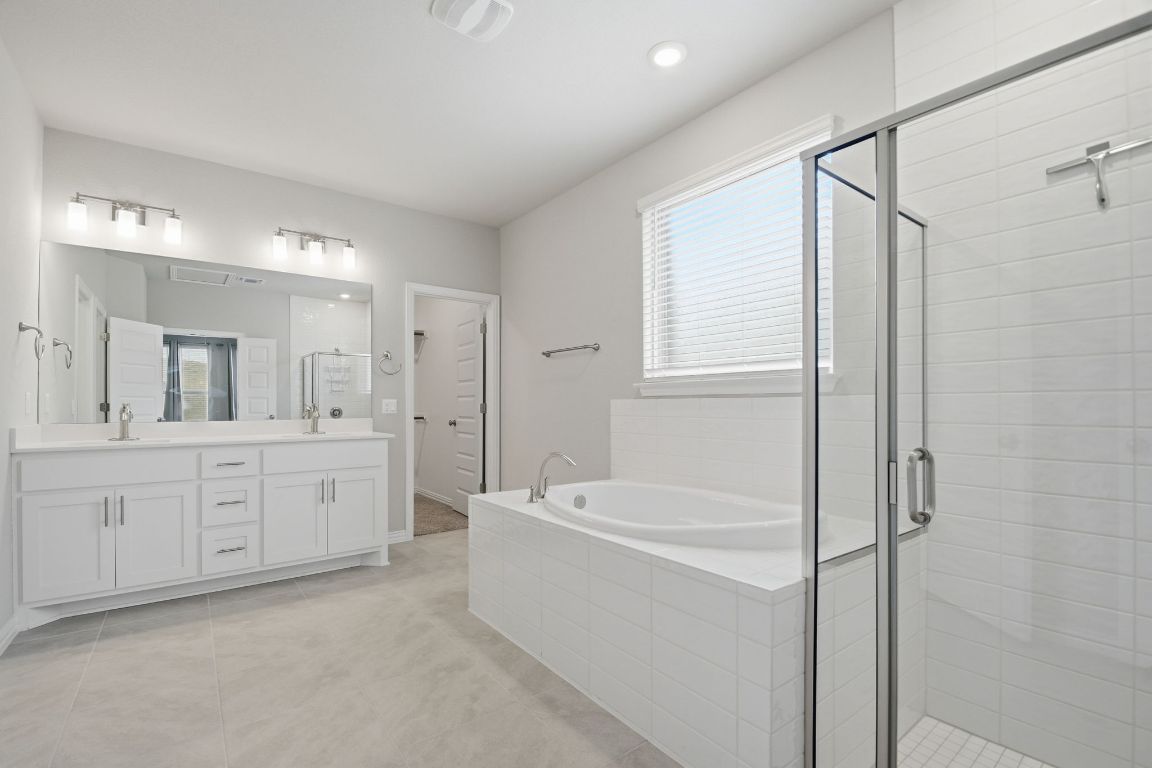 1009 Calendula Trail Georgetown, TX 78628 - Photo 17 of 31 a spacious bathroom with a tub sink a mirror a shower and vanity