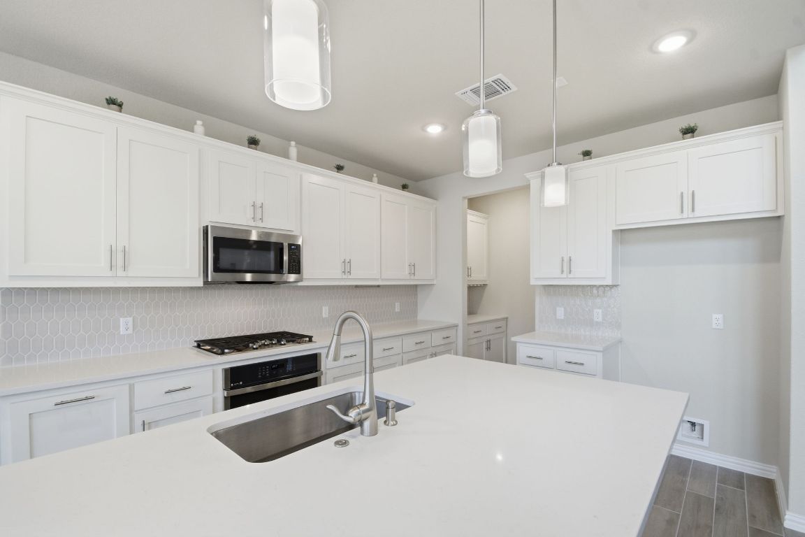 1009 Calendula Trail Georgetown, TX 78628 - Photo 6 of 31 a kitchen with stainless steel appliances a stove a sink a microwave and cabinets