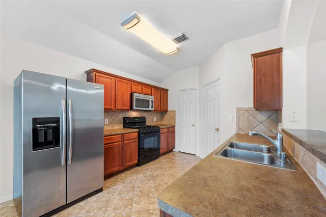 a kitchen with stainless steel appliances granite countertop a refrigerator a stove and a sink