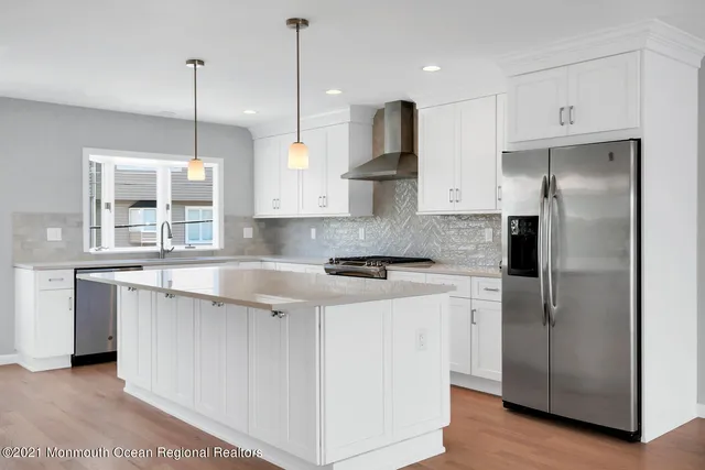 a kitchen with stainless steel appliances granite countertop a sink a stove a refrigerator and island