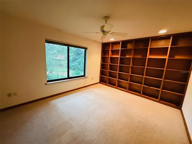 a view of an empty room with a window and a ceiling fan