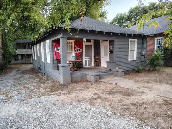 a view of a house with a yard potted plants and a large tree