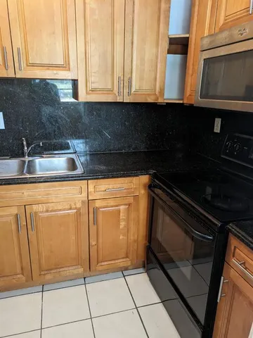 a kitchen with granite countertop white cabinets and black appliances