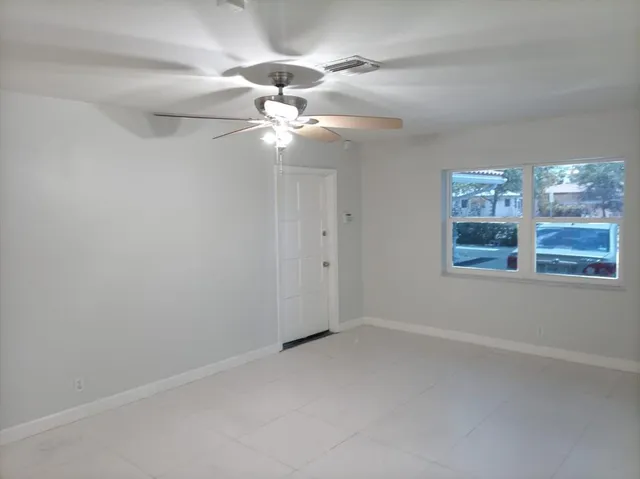 en empty room with windows and ceiling fan