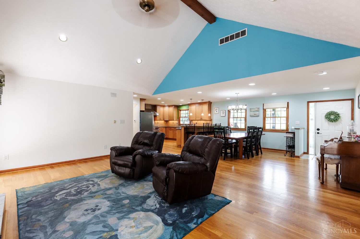 623 Ibold Road Loveland, OH 45140 - Photo 8 of 35 The dramatic great room features soaring vaulted ceilings with exposed beam accents, a cozy wood-burning fireplace, and expansive windows and walkout access to the deck via French doors that fill the space with natural light.
